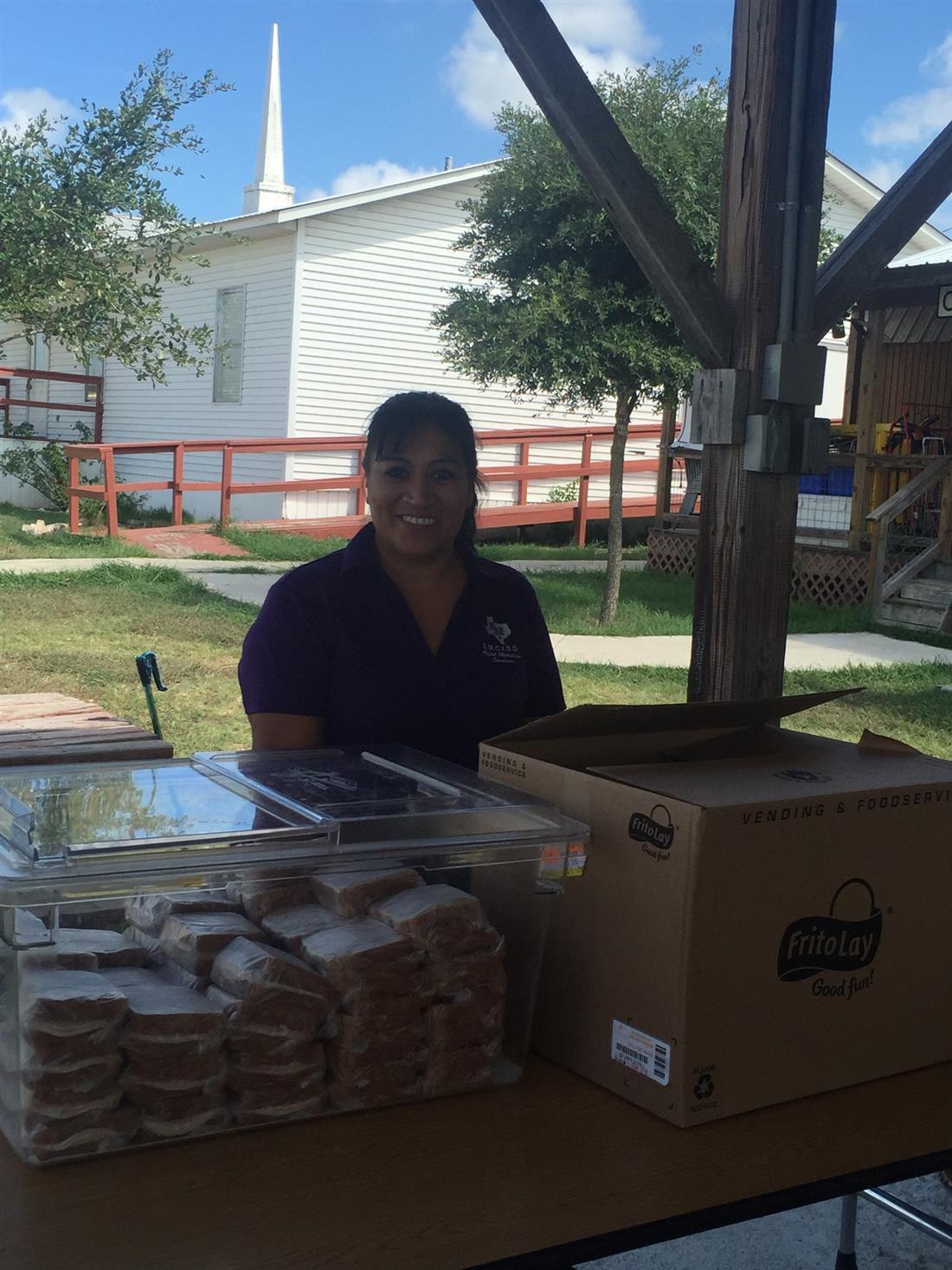 Child Nutrition employee Beatrice serving kids a summer meal.